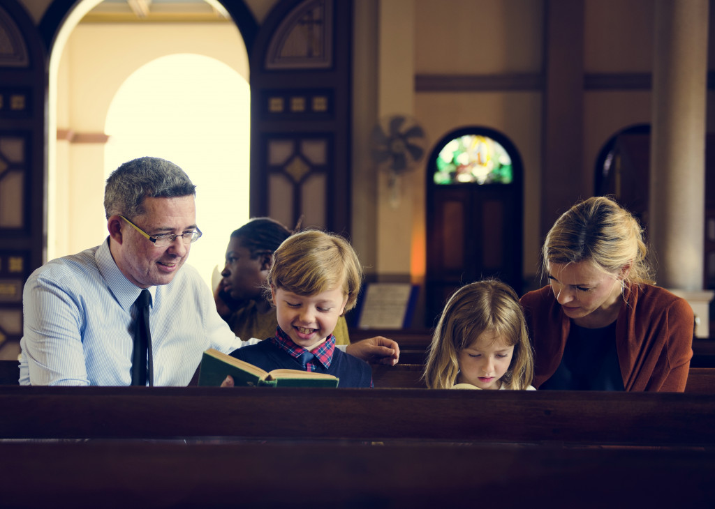 parents teaching children about reading the bible in a church