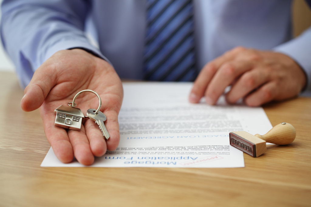 man handling the key to the house with a documents on the table