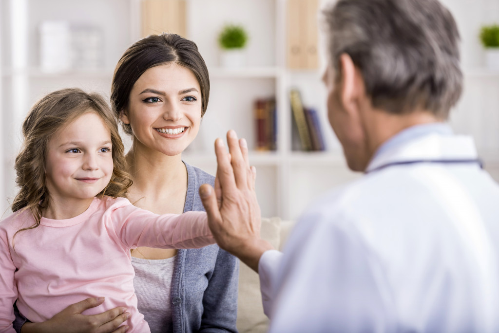 a happy little girl having a high five with a doctor 