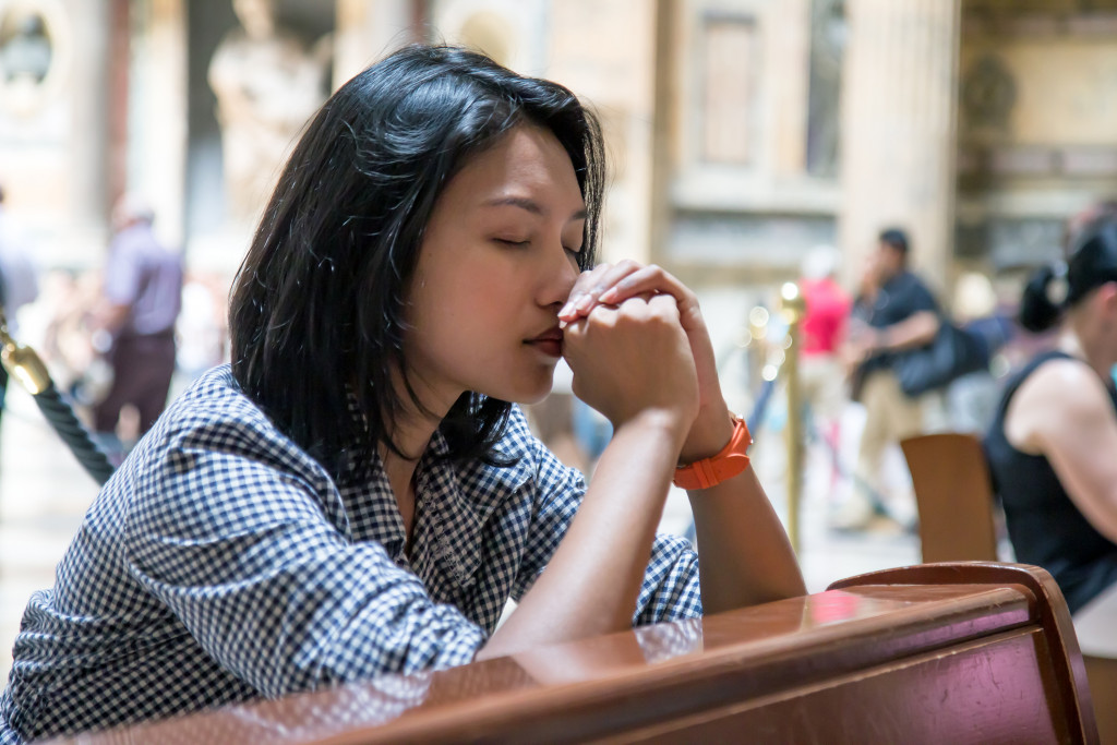 A woman kneeling and praying in a church