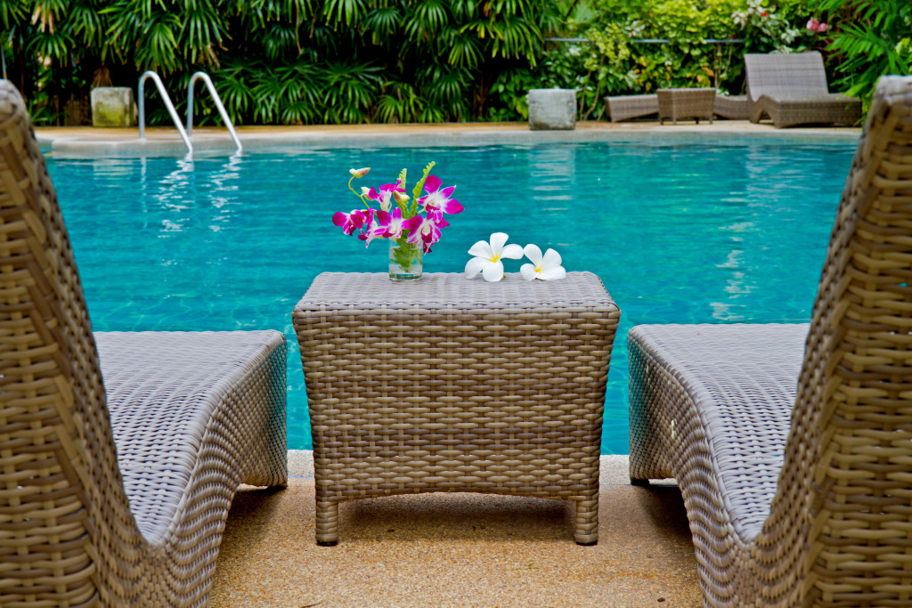 Purple orchid and Frangipani flowers with Rattan chair side swimming pool 