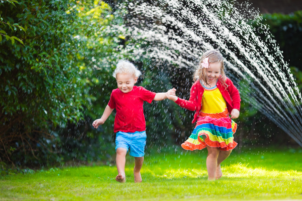 Child playing with garden sprinkler.