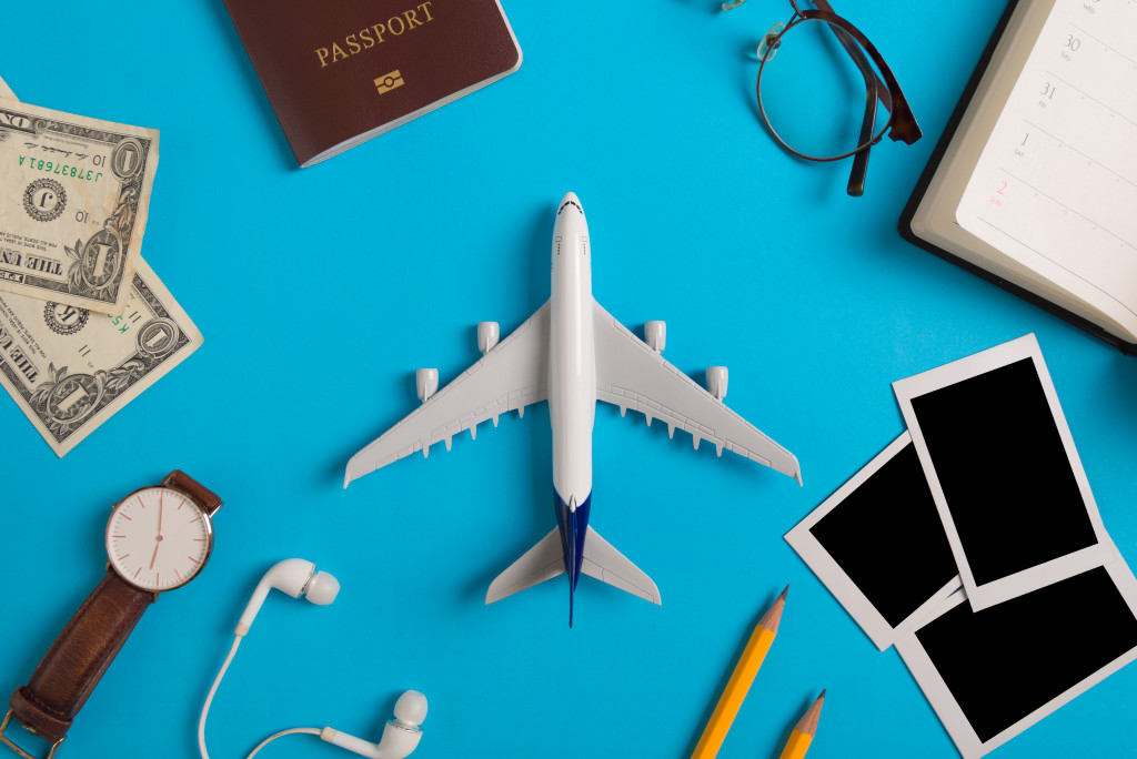 A miniature airplane surrounded by travel items on a blue background