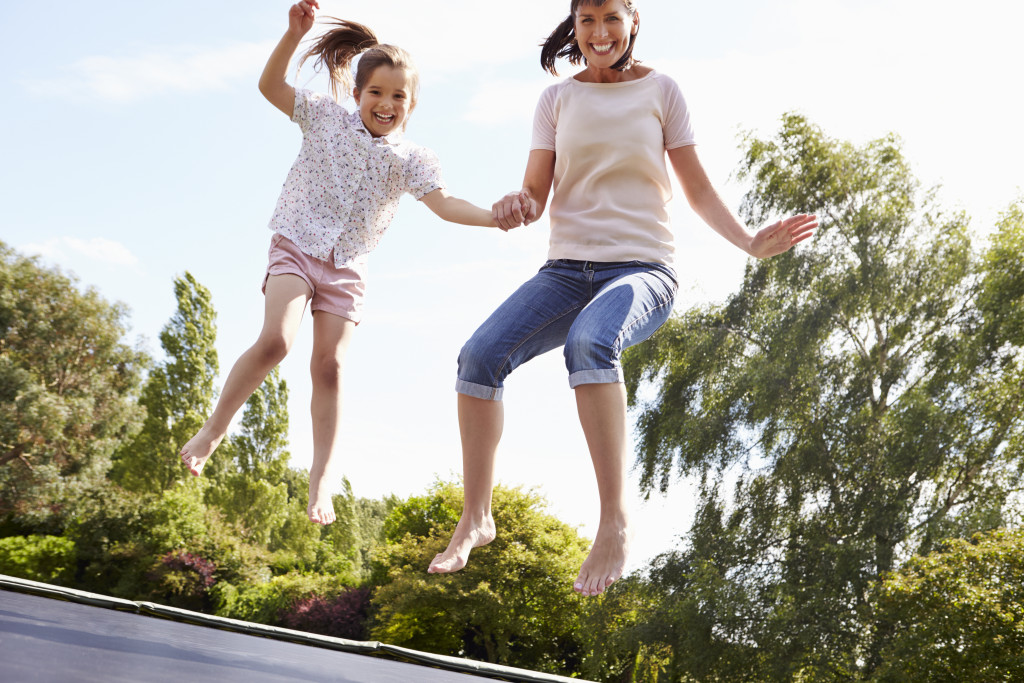 Mother And Daughter Bouncing On Trampoline Together
