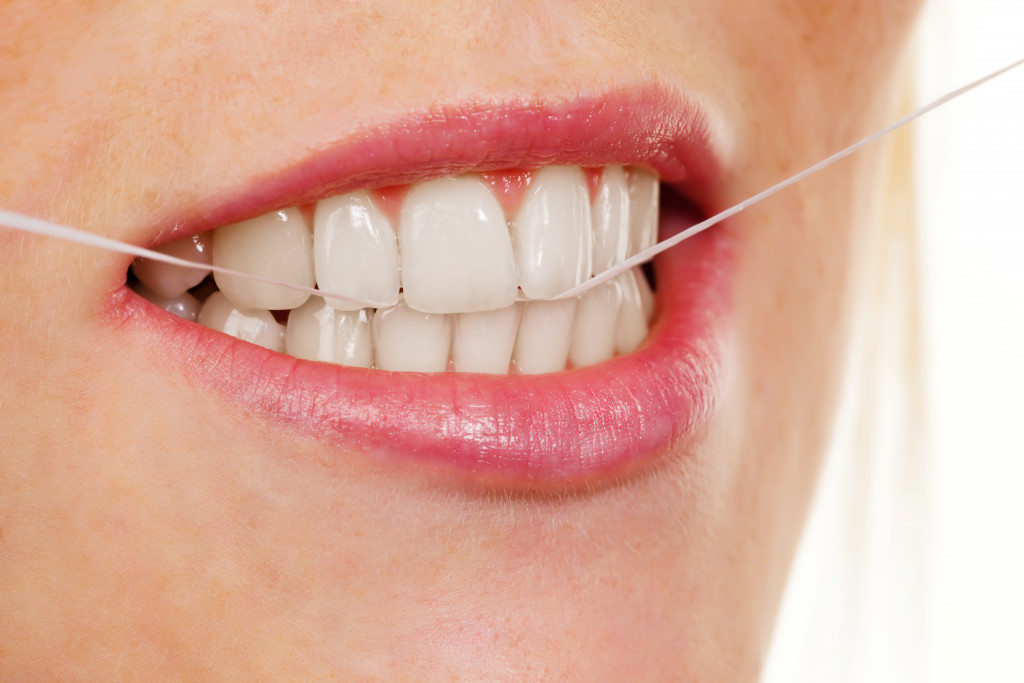 A person with beautiful teeth flossing with a dental floss