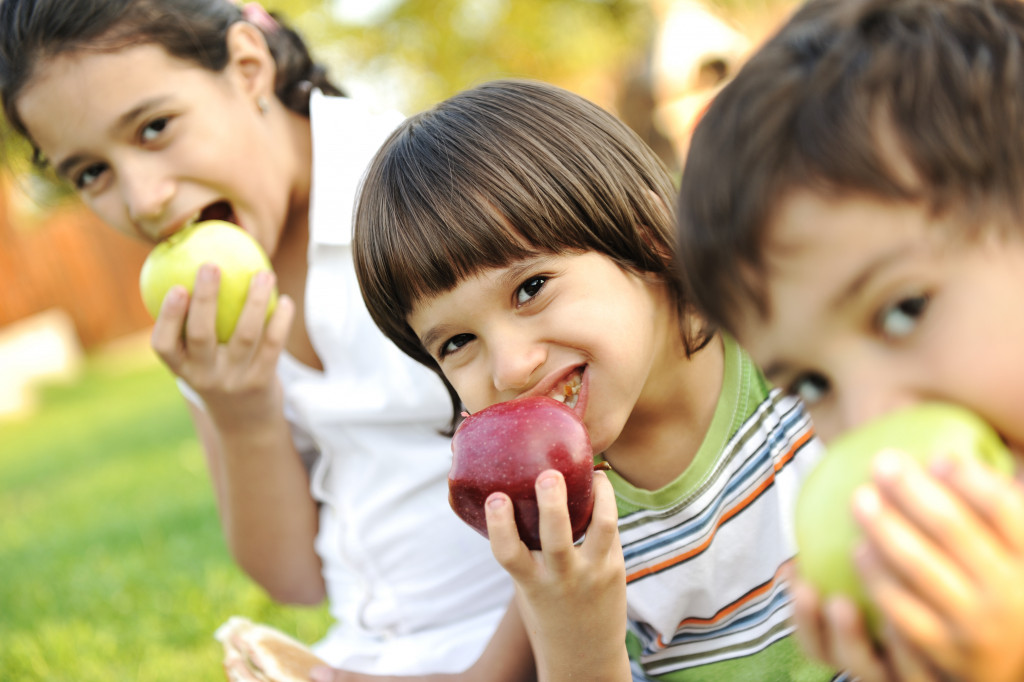 Three kids eating a healthy fruit