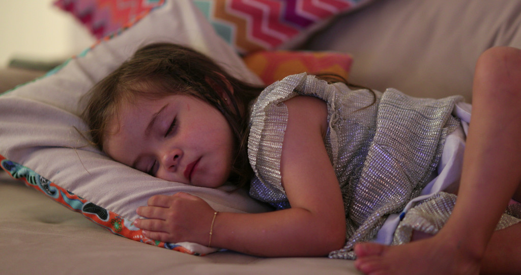 a portrait of a little girl sleeping in bed comfortably
