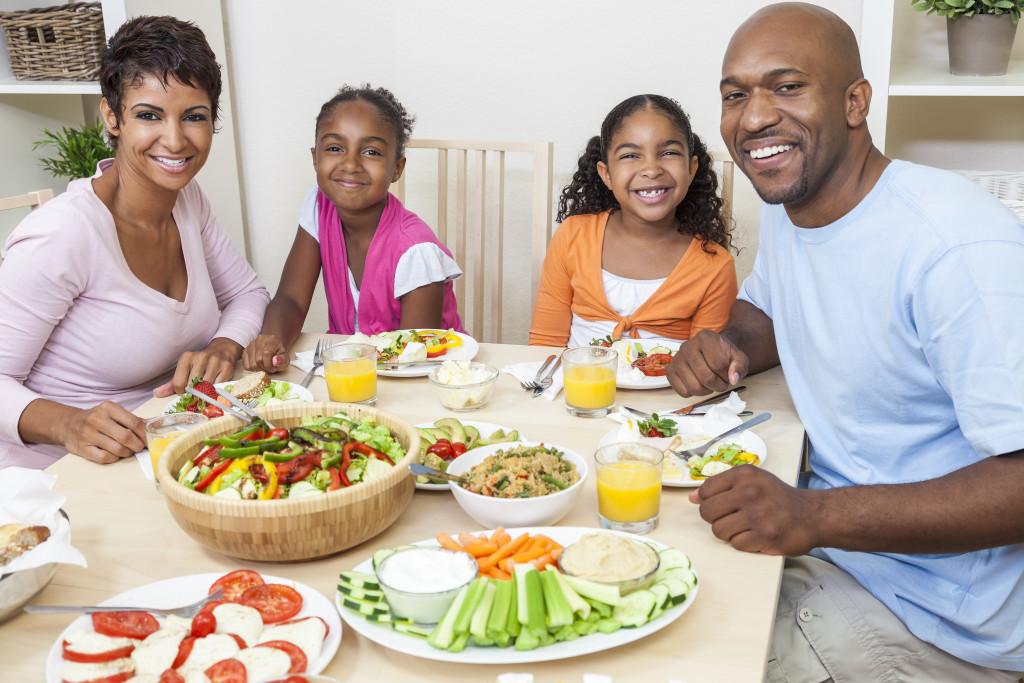 Parents and two children having a healthy meal on their dining room table.
