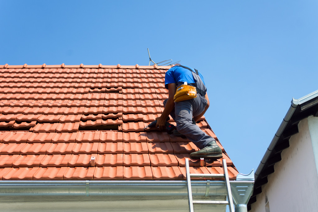 A man using a ladder to repair his roof