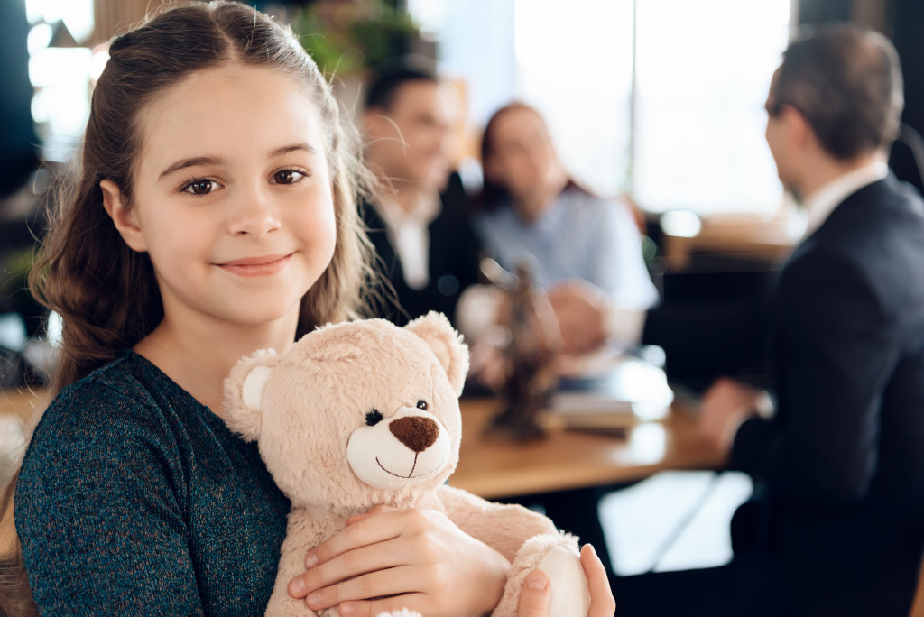 A young girl smiling and hugging a teddy bear