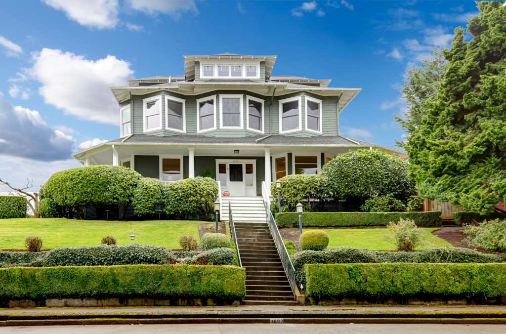 Front of a luxurious home with a landscaped lawn, front stairs, and classic facade. 