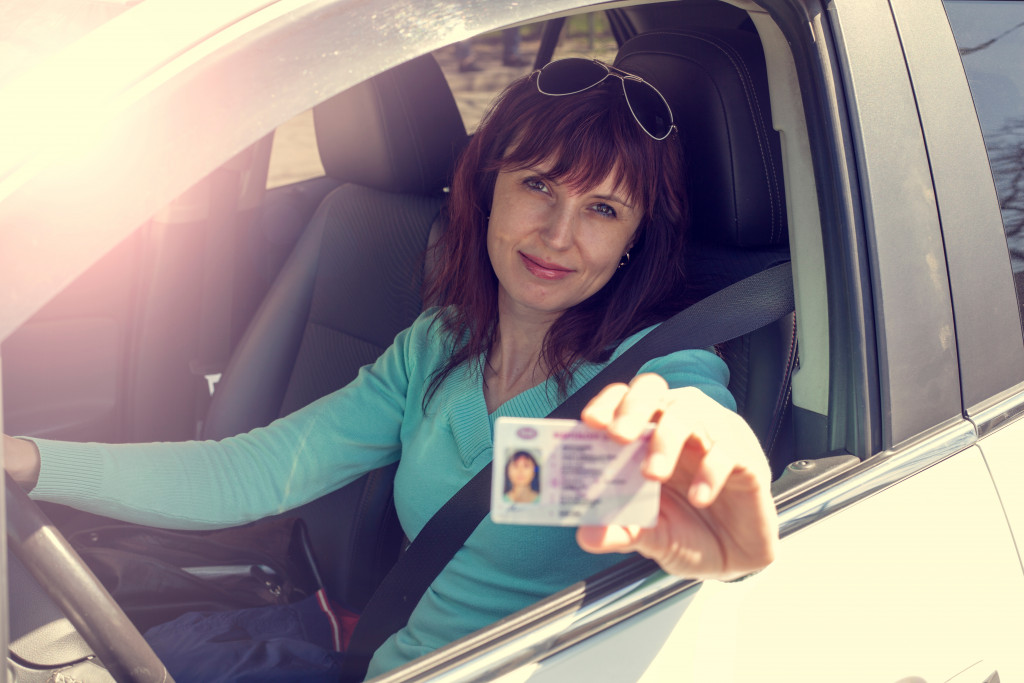 woman driving her car holding her license