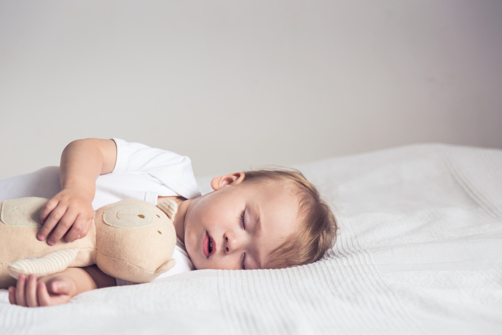 A small cute boy sleeping with his teddy bear 