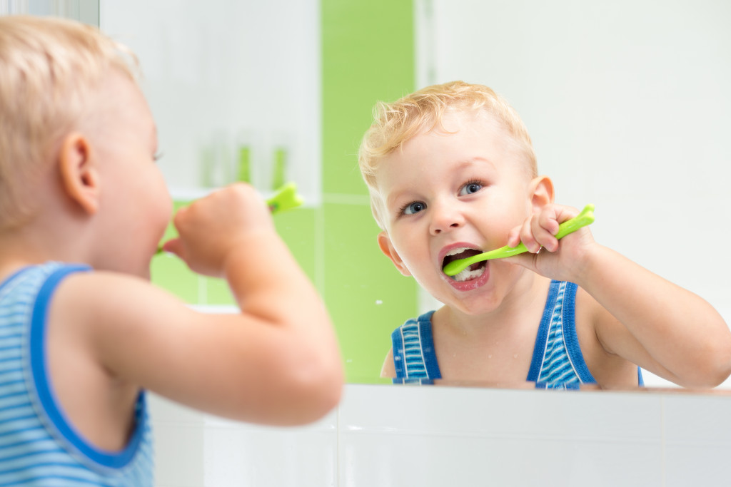 a young boy brushing teeth in front of a mirror