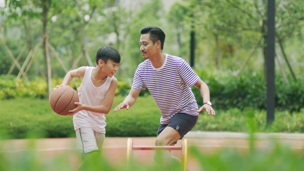 A father and son playing basketball in an outdoor court