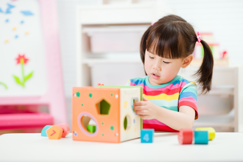 Portrait of a small girl playing with colorful blocks at home