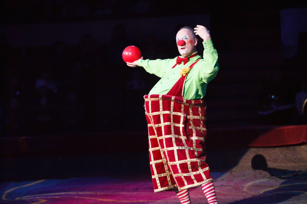 A clown entertainer holding a red ball