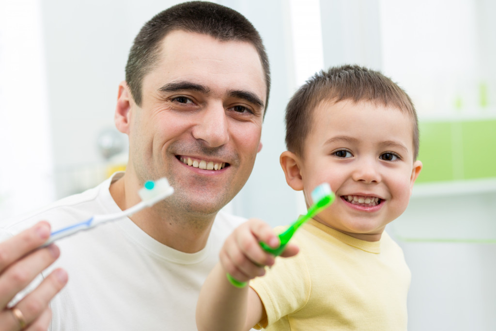 dad with little boy brushing teeth together