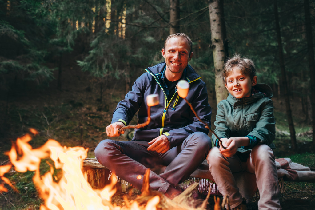 Father and son roasting marshmallows at a campfire.