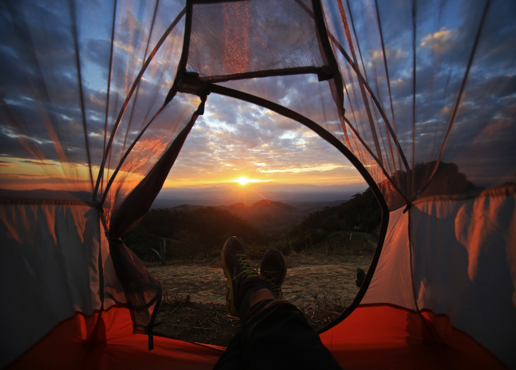 Person lying inside a tent while watching a sunset.