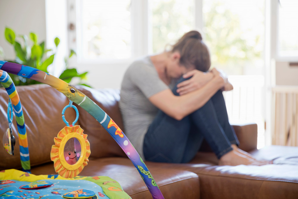 a mother With Post Natal Depression Sits On Sofa