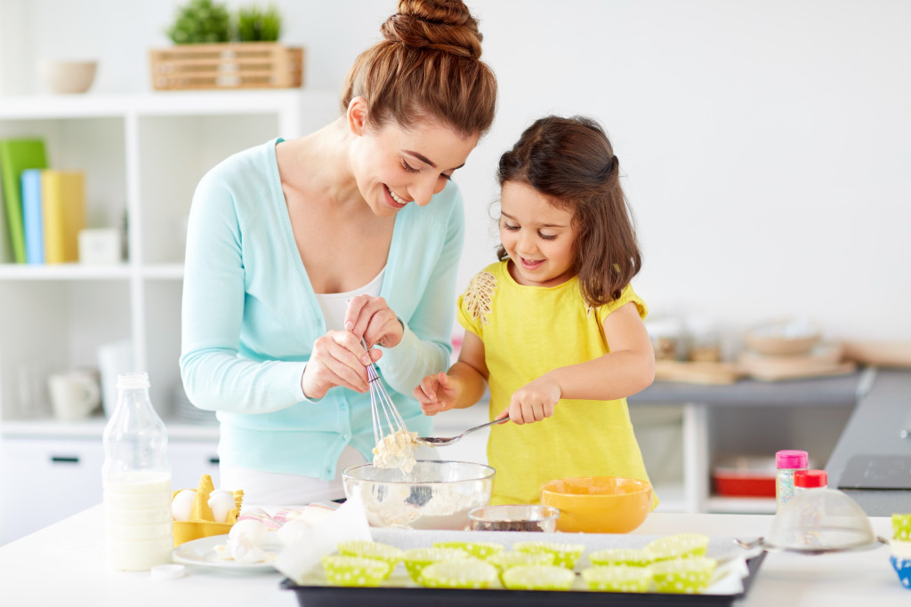 little girl helping mom bake food