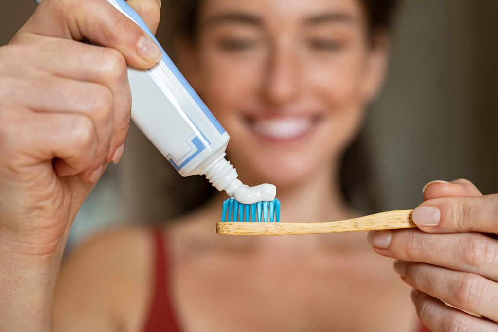 A young woman putting toothpaste on a toothbrush