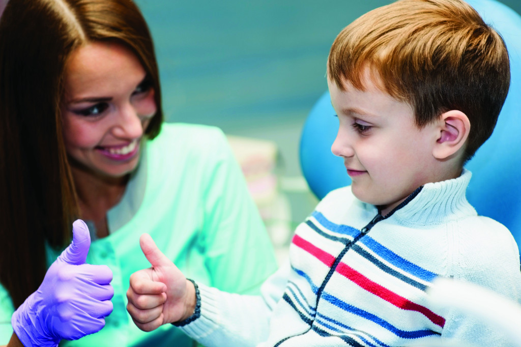young boy giving thumbs up to a female healthcare provider wearing gloves