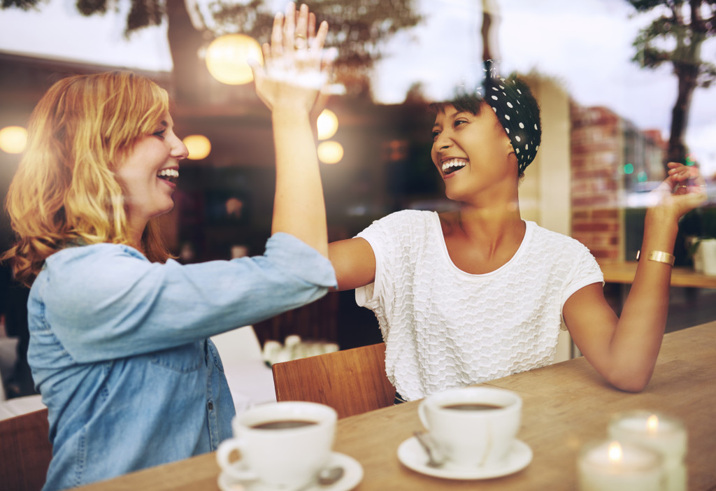 girl having coffee with a friend doing a high five