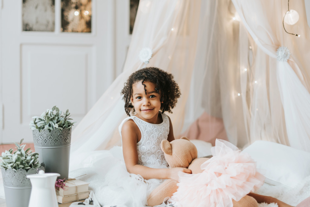 A young girl with natural hair sitting in a teepee in her bedroom