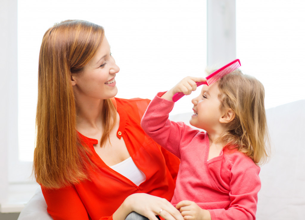 A mother watching her daughter comb her hair